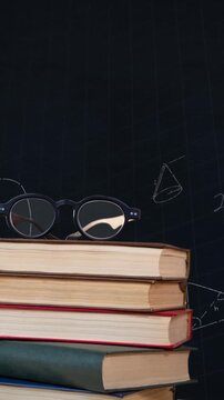 Eyeglass on a pile of books and mathematical equations with figures
