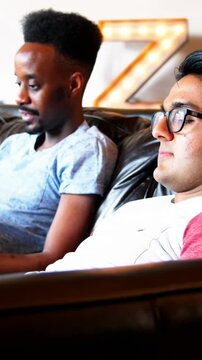 Animation of rainbow heart over gay couple using electronic devices