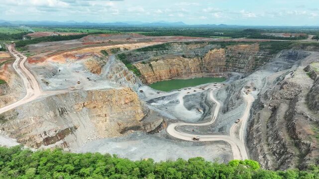 Aerial view captures an extensive gold mining landscape with working machinery and a deep excavation pond, representing heavy industry, mineral extraction, environmental change, resource production.
