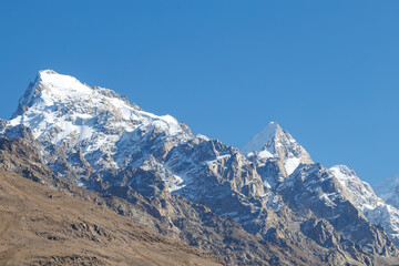 Obraz premium Snow-capped mountain peaks rising sharply against clear blue sky in Pamir Mountains, Tajikistan