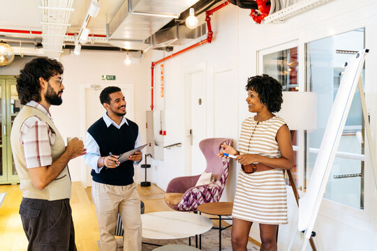 Group of multi ethnic professionals discussing new project, presenting ideas, and brainstorming in modern coworking space