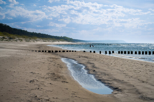 Sandy beach with wooden breakwater groynes in Dziwnow Poland