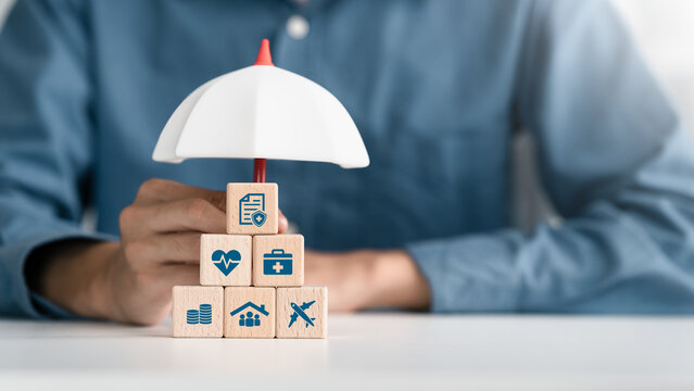 Healthcare, life and travel insurance concept on wooden cube under an umbrella for safety, medical and planning in Future. investment and retirement.