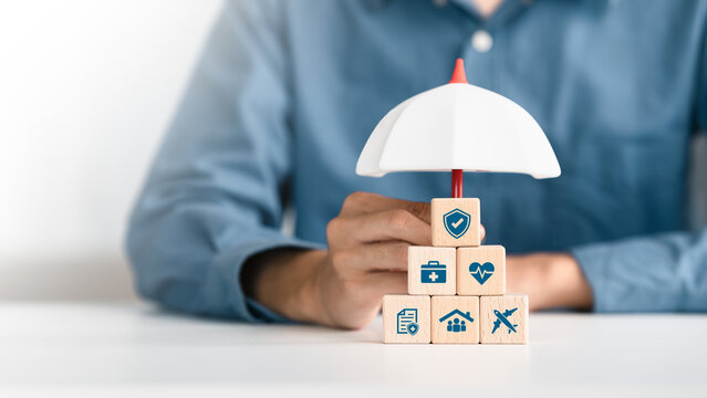 Healthcare, life and travel insurance concept on wooden cube under an umbrella for safety, medical and planning in Future. investment and retirement.