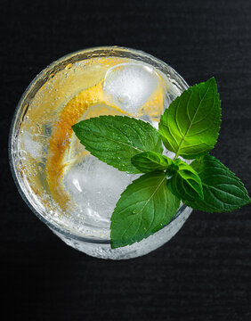 Refreshing Sparkling Citrus Drink With Mint Orange and Ice on Black Background