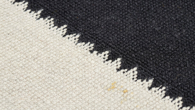 Close up photograph of a textured fabric seam between black and cream tones