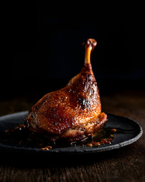 Dark and Moody Shot of Duck Confit on Black Slate Plate in Elegant Presentation