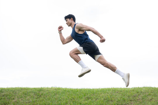 Athletic Asian man in running posture floating over a road along grass field under clear bright sky.