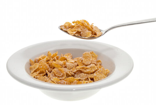 Golden frosted corn flakes served in a white bowl with a silver spoon