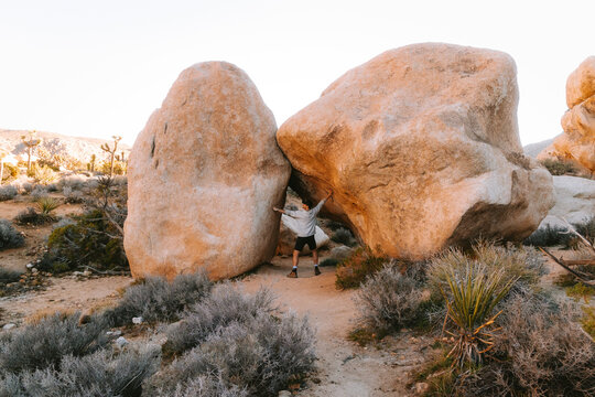 Man holding apart two massive desert boulders