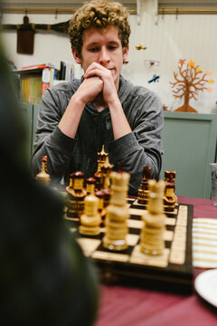 Teenage boy deeply focused on a chess game