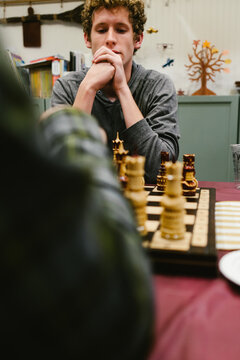Young man with curly hair concentrating on a game of chess