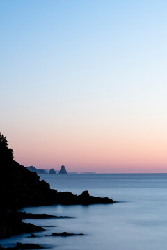 Silhouetted coastal cliffs against a gradient sunset