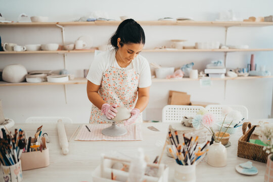 Woman shaping clay in a bright pottery studio