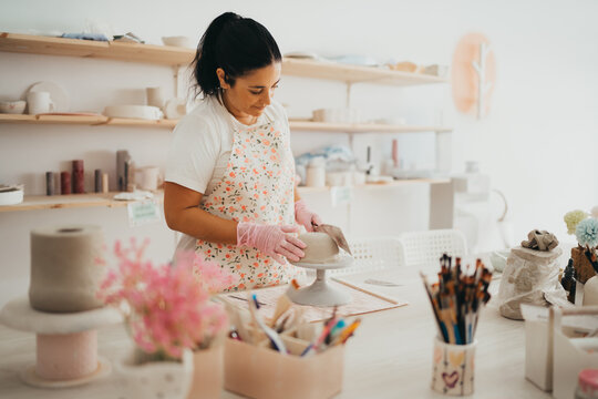 Female artisan shaping clay in a bright studio