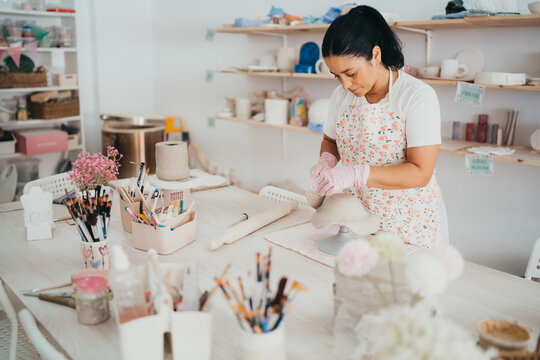 Woman sculpting clay at a workbench in her studio