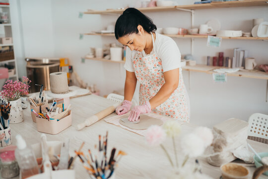 Woman shapes clay in a bright pottery studio