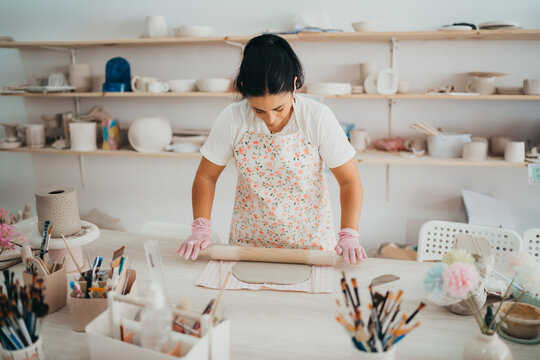 Female artist rolling out clay in a bright workshop