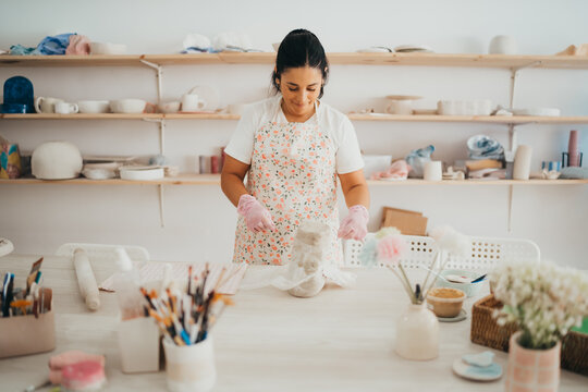 Female potter unwraps clay at workbench in studio