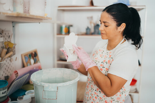 Hispanic Woman cleaning a handmade ceramic piece in her workshop