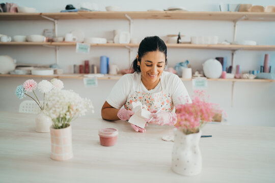 Smiling woman decorating a ceramic piece in a pottery studio