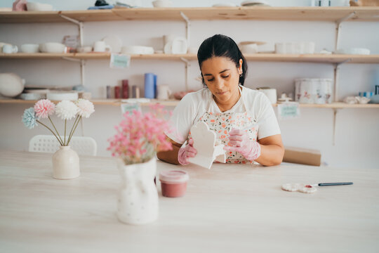 Female artist carefully painting pottery in her studio