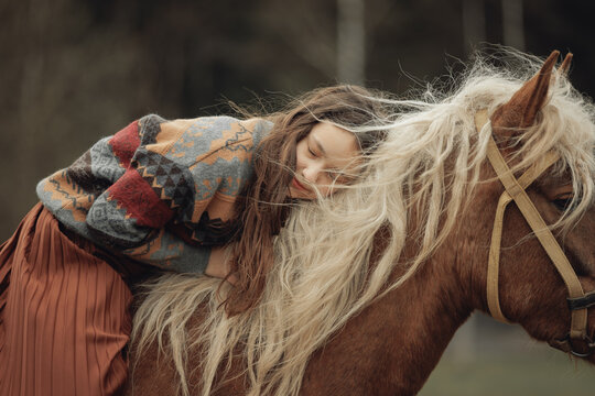 A young girl in a cozy patterned sweater and brown pleated skirt is