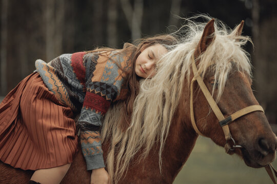 A young girl in a cozy patterned sweater and brown pleated skirt is