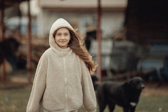 A young girl dressed in a cozy, fluffy jacket with a hood is smiling