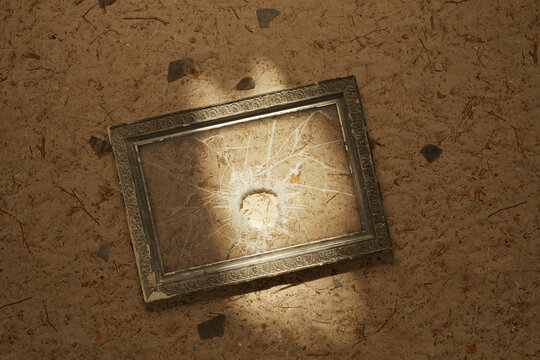 3d rendering of vintage picture frame with a broken glass laying on sandy soil