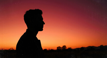Fototapeta premium Silhouette of a man standing against vibrant sunset sky