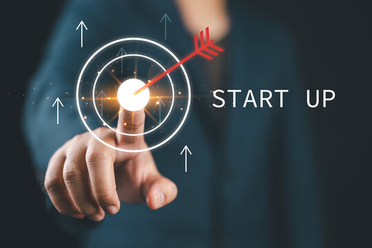 Startup business concept with hand touching target icon and upward arrows on digital background, representing business goals, growth strategy, innovation, success planning, entrepreneurial achievement
