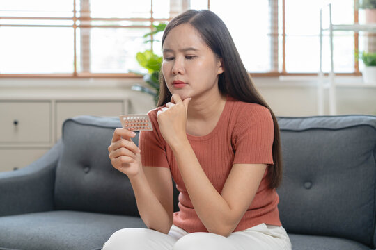 Close up woman holding oral contraceptive birth control pills blister pack and a glass of water, concept of unwanted pregnancy prevention and female healthcare.