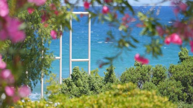 A calm beach scene with a single tree overlooking turquoise waves in 4K slow motion 60fps
