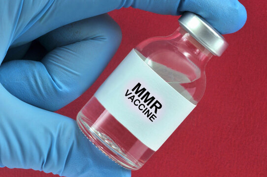 Concept de vaccin contre la rougeole avec  un flacon tenu en main sur fond rouge