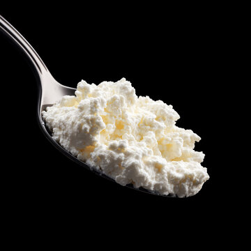 Cottage cheese on spoon isolated on black background with clipping path, presenting concept of healthy nutrition and protein
