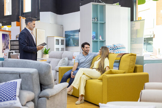 Couple consulting salesperson buying new sofa for home