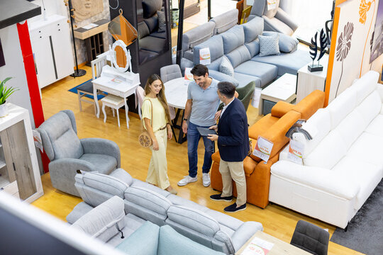 Couple consulting salesperson in furniture store