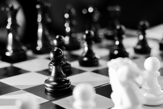 Black chess pawn on board with blurred pieces and dramatic lighting conveying strategy and tension