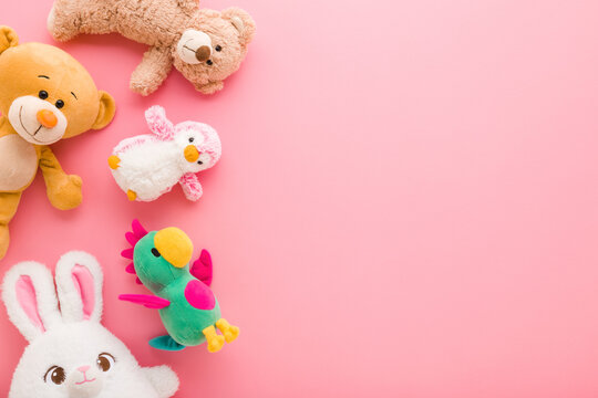 Colorful soft animal toys on light pink table background. Pastel color. Closeup. Empty place for text. Flat lay. Top down view.