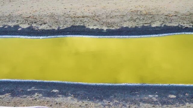 Sustainable Design, harmony of contrast. Miracle in desert. Hydrogen sulfide river. Dead black sludge with band of salt crystals and acid-base aureate water. Beautiful soft color of poisonous water