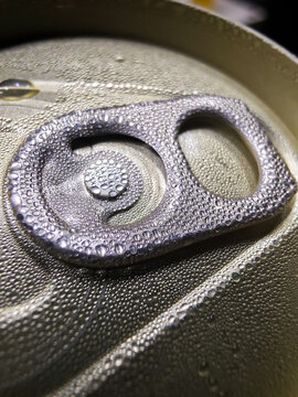 Cold beverage can top with condensation and metal pull tab covered in water droplets, closeup macro texture and reflective surface
