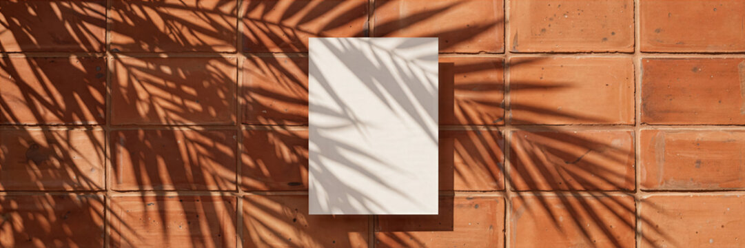 Realistic palm frond shadow overlaying blank vertical card mockup on warm minimalist terracotta tile surface