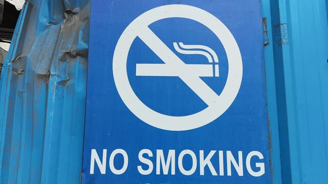 Close up tracking shot focusing on a no smoking symbol and warning board promoting tobacco prohibition and smoke free public spaces