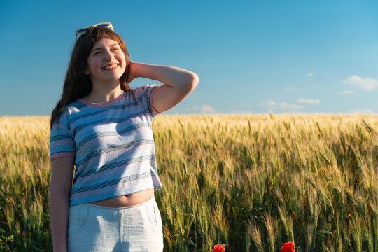 Happy teenage girl enjoying sunny day in wheat field