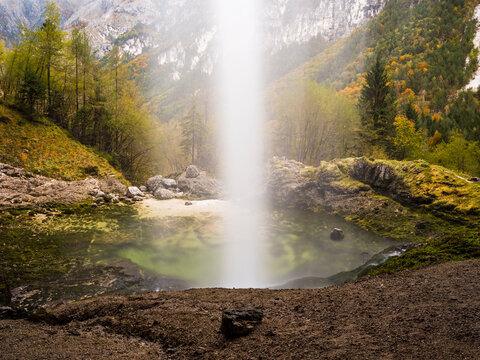 Goriuda waterfall cascades into a clear mountain pool surrounded by an autumn forest, promoting nature tourism and outdoor exploration. Goriuda waterfall, Julian Alps, Chiusaforte, Friuli, Italy.