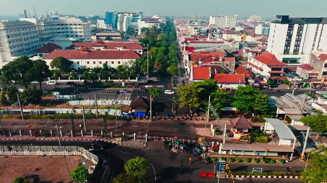 Busy Yogyakarta intersection beside railway station and urban buildings