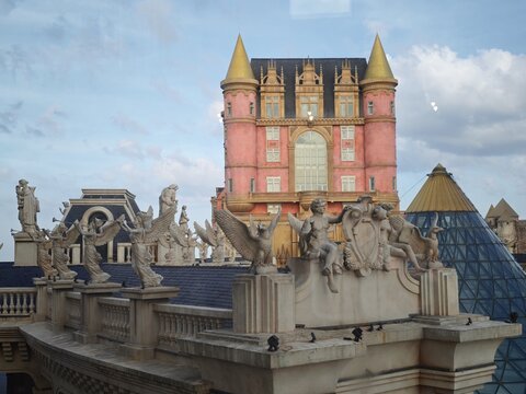 Ba Na, Da Nang, Vietnam - 01 August 2026: View of Ba Na Hills SunWorld with ornate stone statues of angels and mythical creatures on the rooftop against a blue sky.