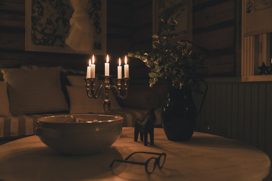 Laane County, Estonia - 31 October 2024: View of a cozy interior on Vormsi featuring a lit candelabra, a bowl, a small horse figurine, and glasses on a wooden table in a rustic room.