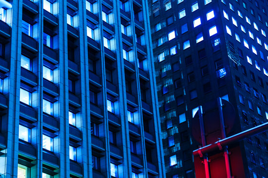 Geometric full-frame architecture texture of illuminated glass and steel skyscrapers at night, ideal for tech background.